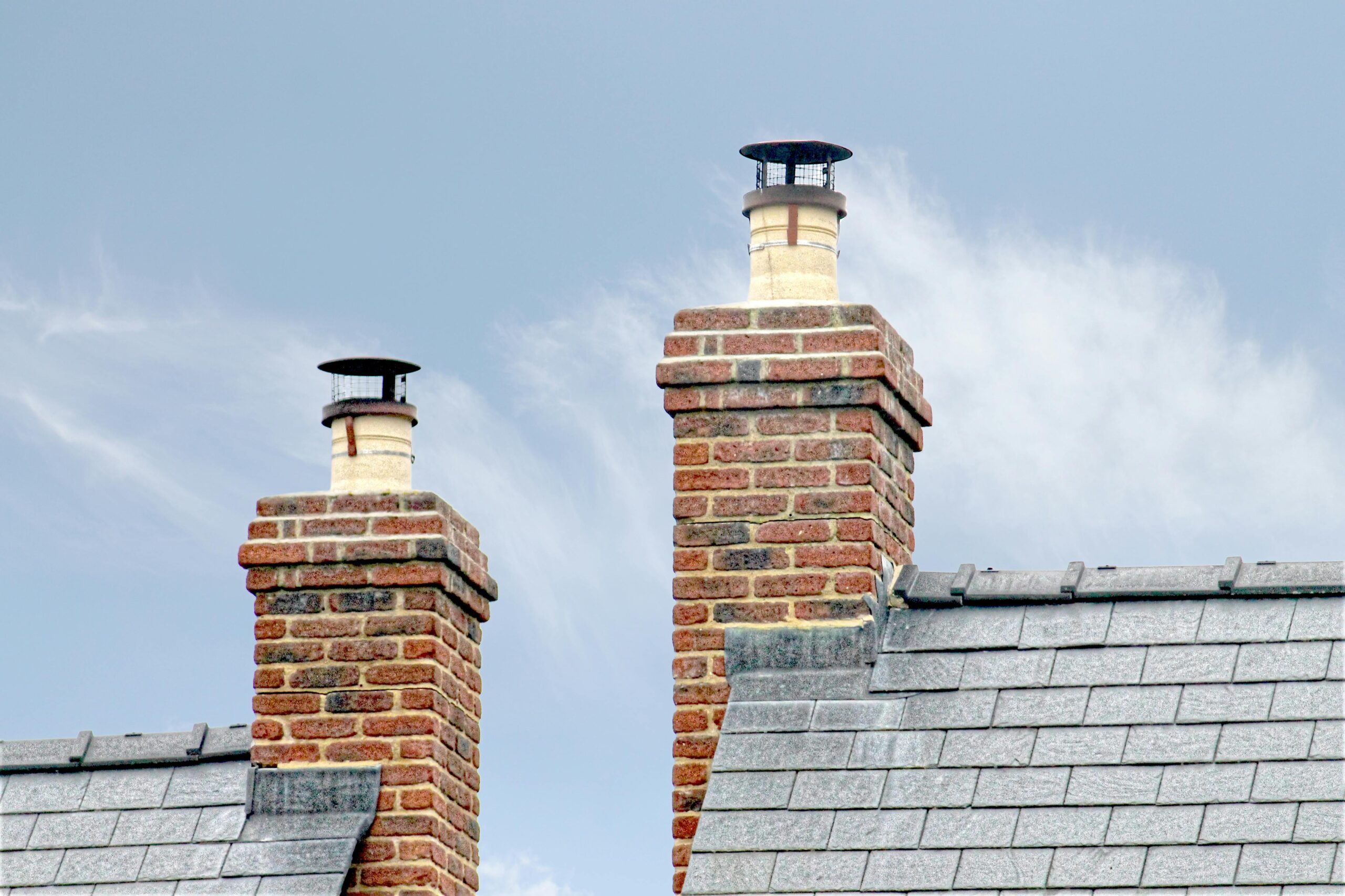 Chimney Repairs & Leadwork Close-up of traditional brick chimneys on a slate roof, England.