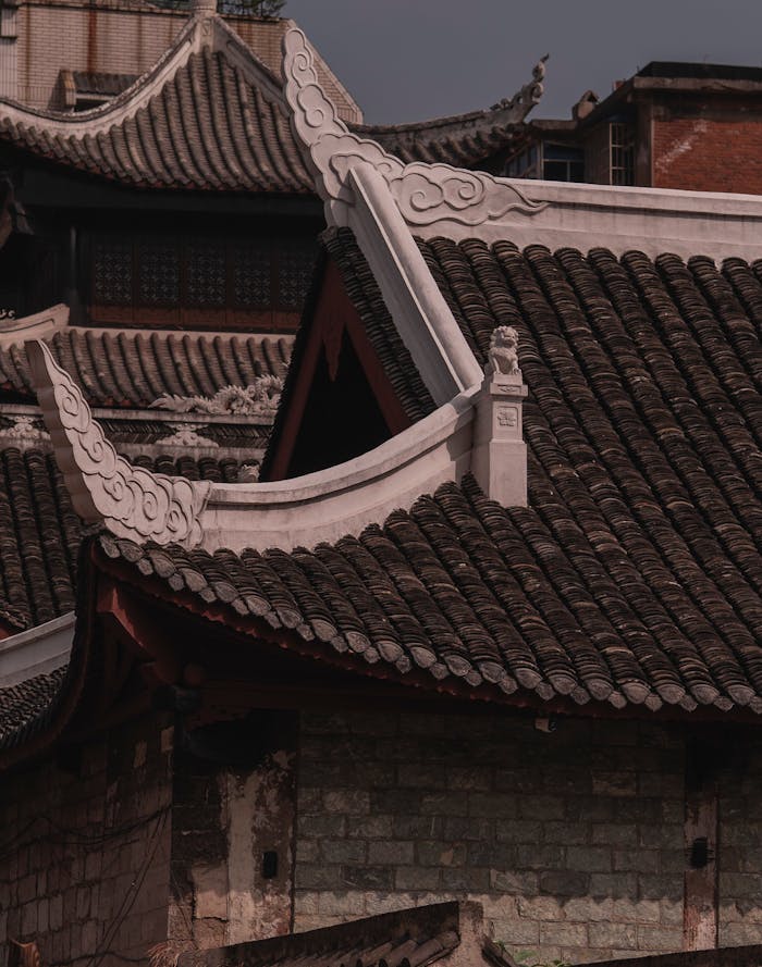 Close-up of traditional Asian architecture featuring ornate, tiled roofs under a muted sky.