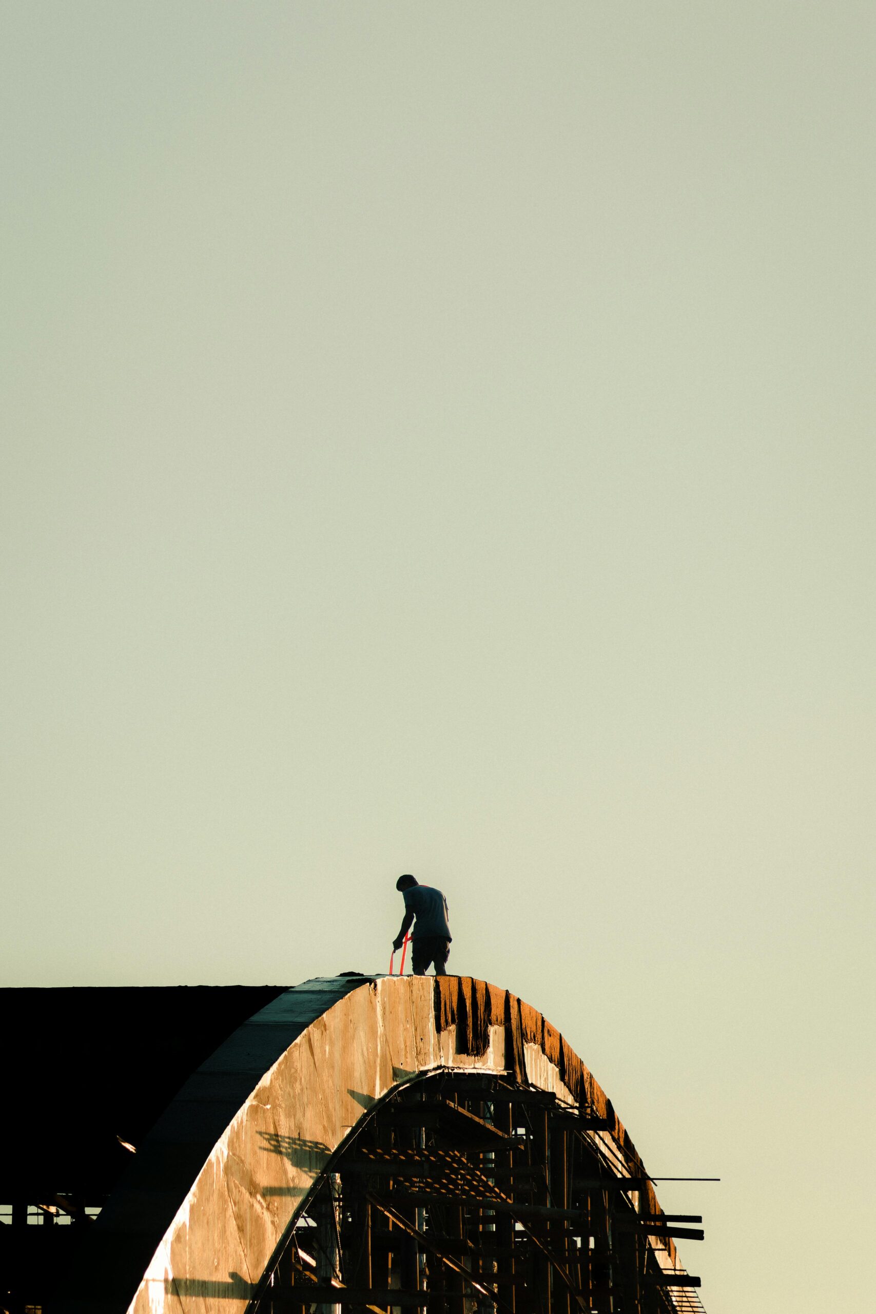 Roof Repairs Silhouette of a construction worker on a bridge in Chilmari, Bangladesh at sunset.