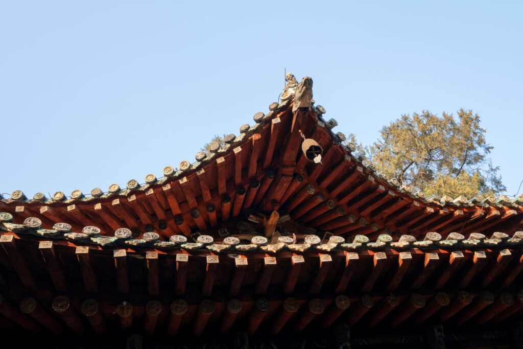 Close-up of a traditional Asian roof with intricate tiles and clear blue sky.