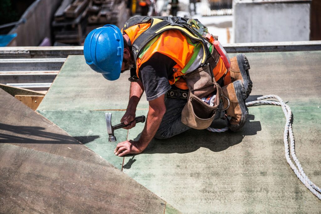 pexels photo 544966 544966 A skilled construction worker in protective gear hammering a rooftop panel.