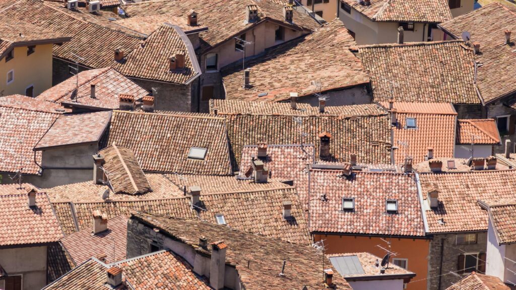Close-up aerial shot of traditional European terracotta rooftops under bright sunlight.