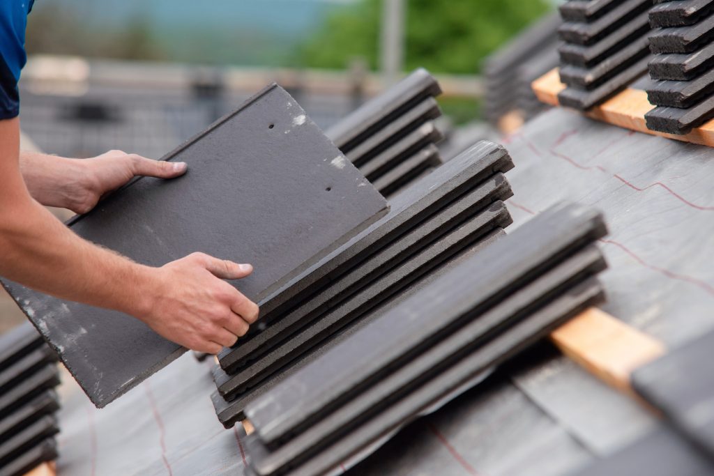 roofer,working,on,residential,roof,carefully,placing,and,securing,slate