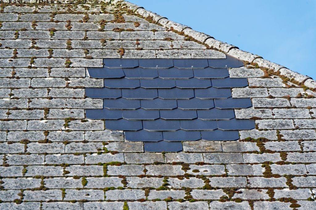 a,weathered,stone,roof,covered,in,moss,with,a,patch
